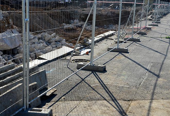 a construction worker carrying a temporary fence panel to put in place